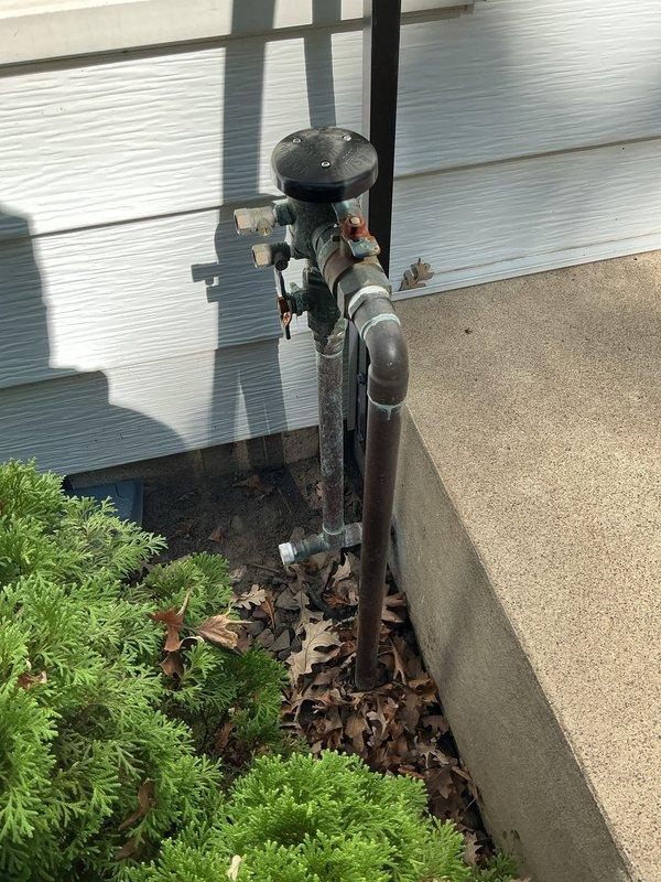 Inspected property for reported water leak at washer hookups. Identified multiple leaking gate valves requiring immediate attention. Conducted diagnostic assessment of equipment room plumbing system and documented deteriorated exterior plumbing connections including weathered pipe assembly and improperly sealed wall penetration. Recommended comprehensive equipment room repipe to address systemic valve failures and prevent future leaks.