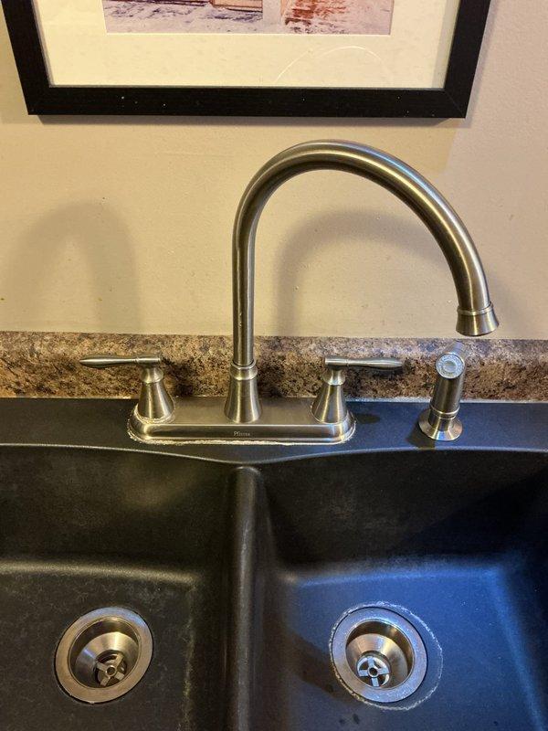 Responded to service call regarding leaking kitchen faucet. Upon inspection, determined existing faucet needed replacement rather than repair. Successfully removed old double-handle chrome faucet and installed new brushed nickel high-arch faucet with side sprayer on granite countertop with double-basin composite sink. Tested new fixture for proper operation and verified no leaks.
