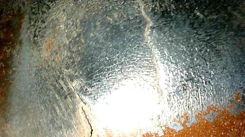 Conducted insurance inspection following house fire and discovered a large crack on the backside of the heat exchanger, evidenced by visible fracture lines in the metal surface and significant deterioration including corrosion. Tagged out the furnace as unsafe for operation and scheduled follow-up appointment for replacement equipment quotation.