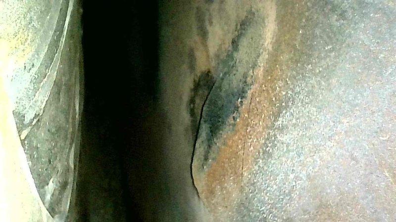 Conducted insurance inspection following house fire and discovered a large crack on the backside of the heat exchanger, evidenced by visible fracture lines in the metal surface and significant deterioration including corrosion. Tagged out the furnace as unsafe for operation and scheduled follow-up appointment for replacement equipment quotation.