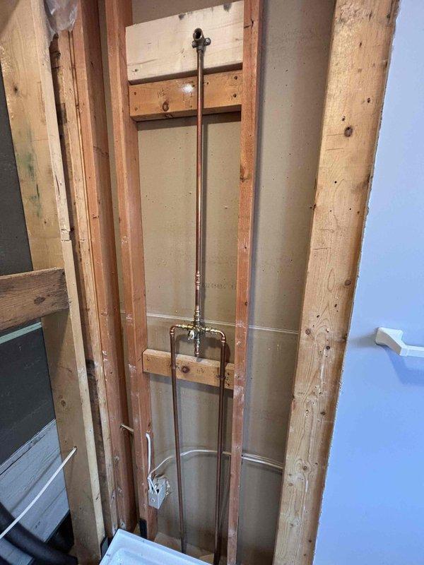 Completed installation of customer shower pan with mortar mix, installed shower valve, and performed rough-in plumbing work for the shower assembly. Work included cutting access to existing plumbing, mounting valve fixture with copper pipe connections, and preparing the floor for proper shower pan installation.