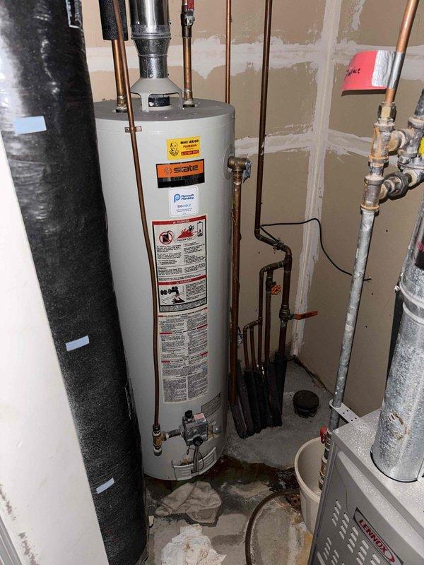 Replaced 31-year-old water heater that had a compromised tank causing leakage and floor damage in bathroom area. Customer had proactively shut off water supply valve to prevent further leaking. New water heater installed in utility area with proper copper pipe connections and tested for functionality.