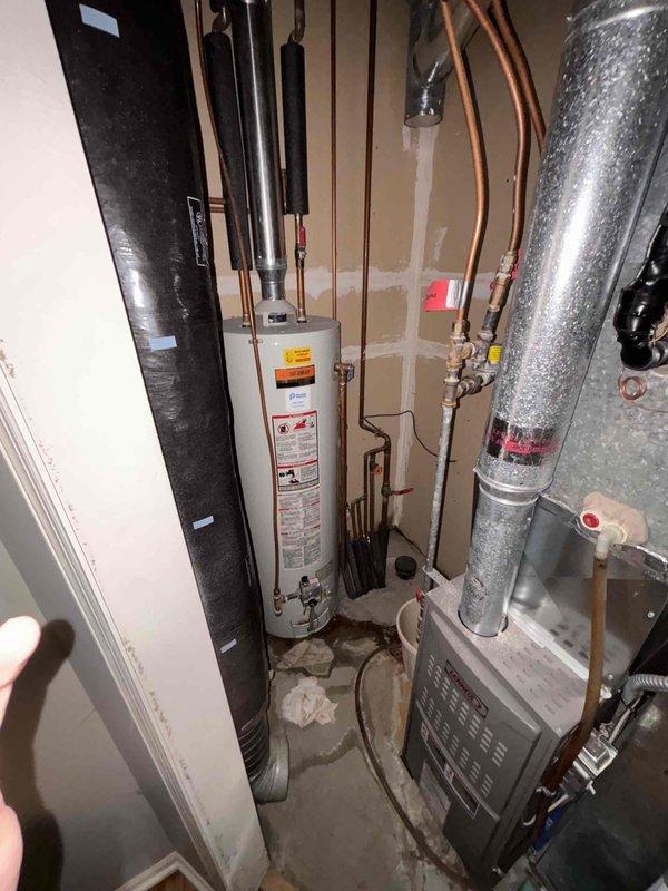 Replaced 31-year-old water heater that had a compromised tank causing leakage and floor damage in bathroom area. Customer had proactively shut off water supply valve to prevent further leaking. New water heater installed in utility area with proper copper pipe connections and tested for functionality.