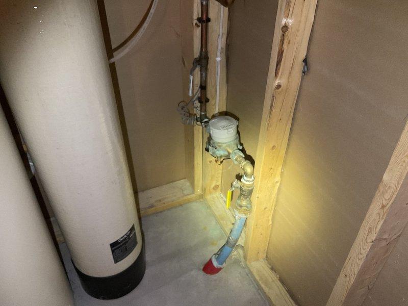 Performed water treatment system assessment for customer whose current water softener was failing and leaking (currently bypassed). Inspection of utility area revealed exposed plumbing infrastructure with existing water filtration components. Evaluated installation requirements considering current PVC piping configuration and meter setup in partially finished utility space. Provided comprehensive estimate for new water treatment system replacement.