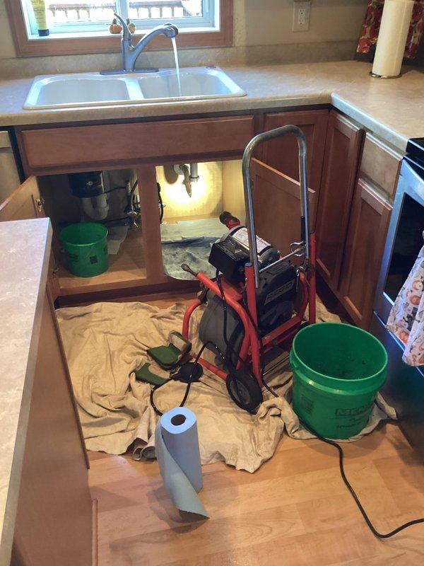 Responded to a service call regarding water leak between garbage disposal and kitchen drain pipe. Diagnostic inspection revealed significant leakage during disposal operation and a clogged kitchen drain. Deployed drain snake equipment to clear blockage and repaired the connection between disposal unit and drain pipe, eliminating leak. Verified proper function with water test.