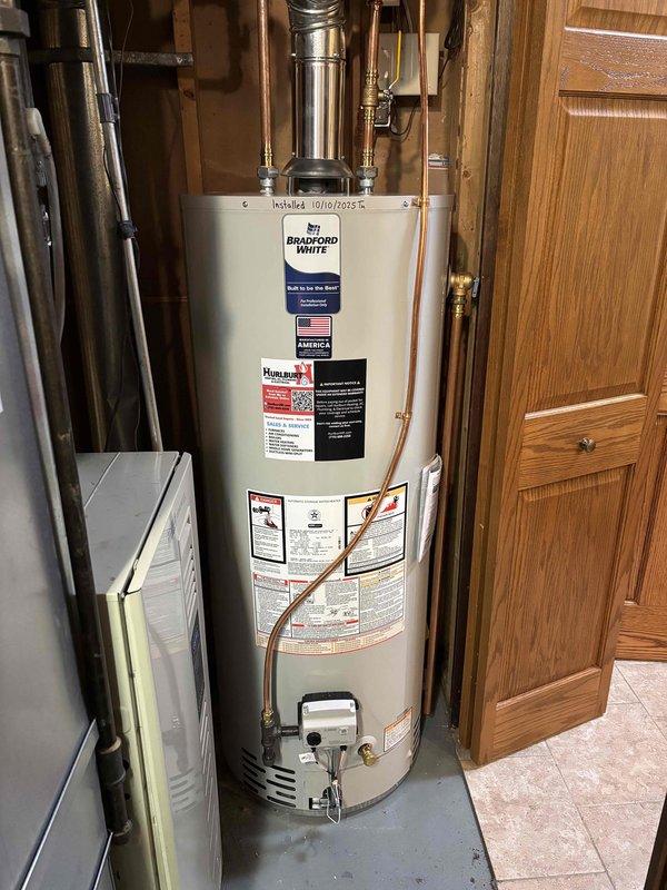 Diagnosed water leak at base of 14-15 year old 50-gallon water heater. Determined tank was rusting out, causing leakage. Replaced aging water heater with new Bradford White unit, installed all necessary copper supply lines and ventilation components, and verified proper operation of the new system.