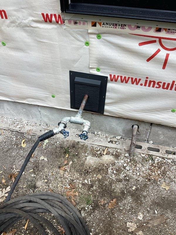 Completed installation of a new frost free hose bibb after cutting back the existing spigot from the rock wall removal area. Work included connecting the new frost free fixture to the existing plumbing infrastructure visible in the crawlspace, ensuring proper installation through the house wrap barrier during the ongoing construction phase.