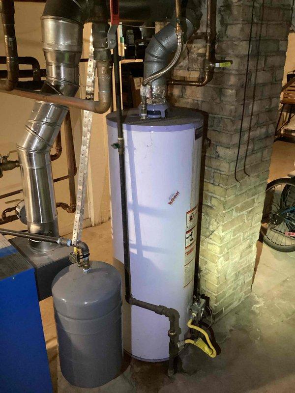 Replaced leaking 40-gallon natural gas tank water heater with customer-approved 50-gallon model. Original unit showed visible water pooling at base and significant bottom corrosion. New installation included proper connections to existing gas line and ventilation system, with all plumbing connections tested for leaks.