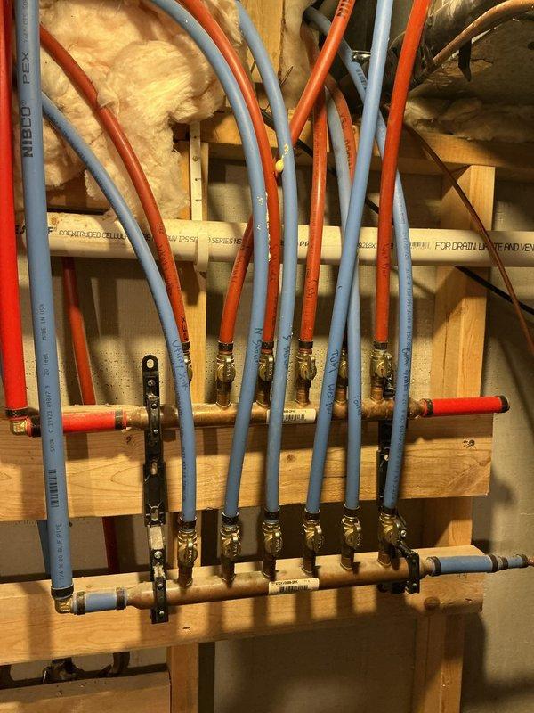 Performed comprehensive water tune-up service, including descaling clogged rainfall showerhead to restore water pressure. Properly secured loose shower trim plate with silicone to prevent spinning. Addressed rumbling toilet by tightening loose toilet lever. Noted high water pressure and absence of water treatment system during inspection of home's PEX distribution manifold.