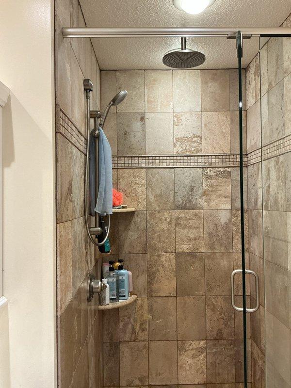 Performed comprehensive water tune-up service, including descaling clogged rainfall showerhead to restore water pressure. Properly secured loose shower trim plate with silicone to prevent spinning. Addressed rumbling toilet by tightening loose toilet lever. Noted high water pressure and absence of water treatment system during inspection of home's PEX distribution manifold.