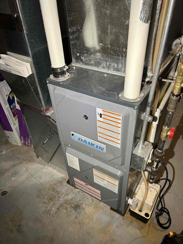 Performed comprehensive furnace tune-up on approximately 5-6 year old natural gas Daikin system. Addressed several issues including extremely clogged air filter, flame sensor covered with white debris, high gas pressure on low setting, and extended high stage delay time (~10 minutes). Cleared condensation drain line, verified proper pump operation with no blockages, replaced air filter, and adjusted both low and high stage pressure settings. Final inspection confirmed safe carbon monoxide levels.