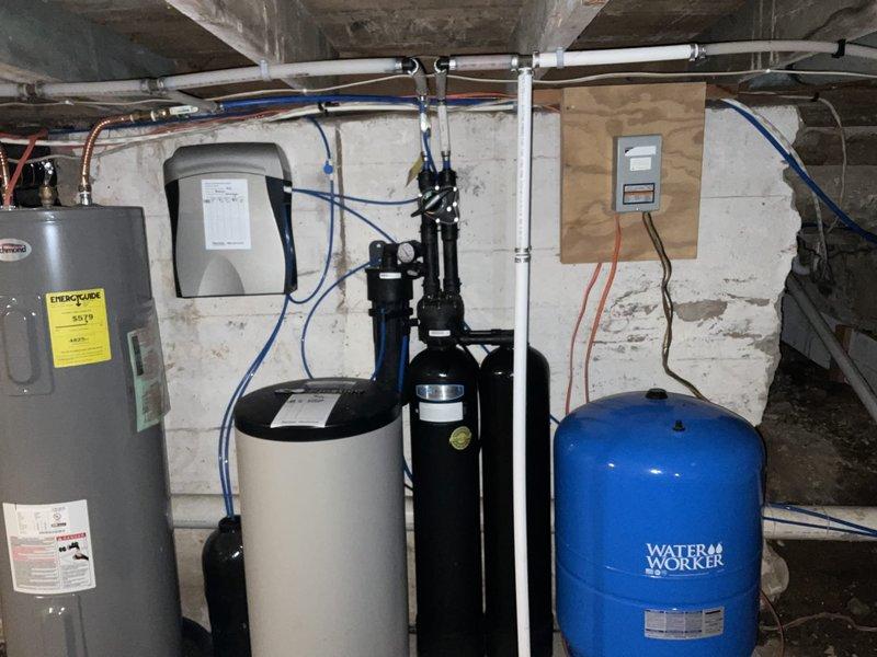 Conducted recurring plumbing inspection of residential water treatment system. Examined water heater, water softener unit, dual black water treatment tanks with pressure gauges, and Water Worker expansion tank. All components and associated PVC piping and water lines appear to be functioning properly with no visible leaks or irregularities noted.