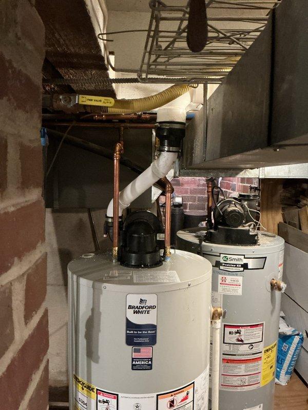 Replaced leaking 8-year-old 50-gallon power vent natural gas water heater with a new Bradford White model. Installation included proper connection of copper water lines, PVC venting, and yellow flexible gas line in the utility room.