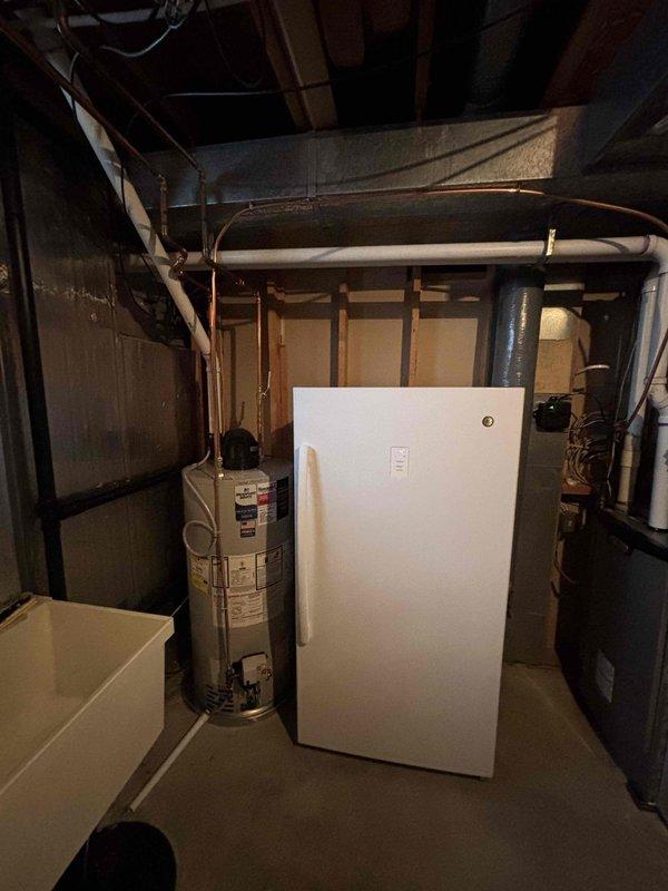 Completed warranty service to replace a plastic water heater drain pan with a metal one as part of previous installation. Relocated gas line closer to ceiling and performed full water heater swap-out in utility area with exposed framing.
