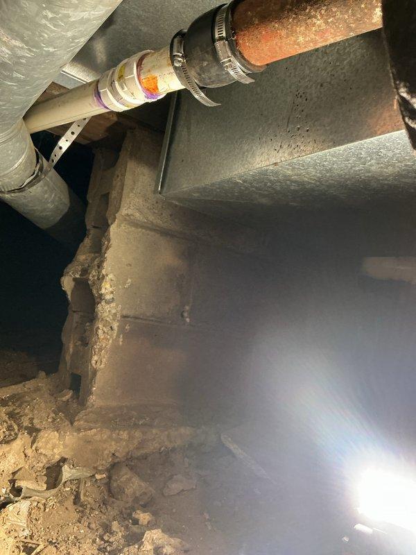 Responded to a leaky toilet issue reported by customer, which investigation revealed was caused by clogged lines resulting from improperly graded sewer pipes in poor condition. After assessment, provided a comprehensive solution that included complete re-piping of the affected plumbing system. Documented the repair area showing corroded copper pipes with significant oxidation in the crawlspace/basement and deteriorating concrete foundation surrounding the plumbing infrastructure, all of which was successfully replaced with new PVC piping to restore proper drainage function.