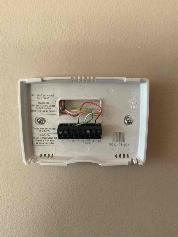 Installed replacement thermostat per service order #193077-001, completing wiring connections and proper mounting of new unit. Existing wires (R, C, G, Y, W, O/B) were properly terminated to the corresponding terminals on the new thermostat base. Service required follow-up visits to complete installation.