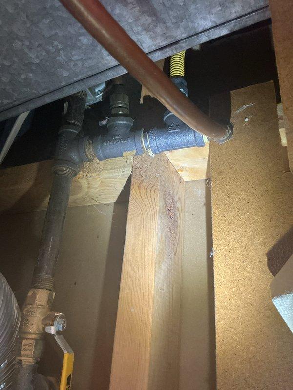 Performed comprehensive inspection of reported gas leak at client's furnace supply line. After thorough assessment using detection equipment, no active gas leaks were identified in the system. Also investigated sewer line for reported root intrusion; visual inspection confirmed no current blockage from tree roots. Documentation photos taken of existing plumbing assembly showing copper supply lines, valves, and connection points in structural space.