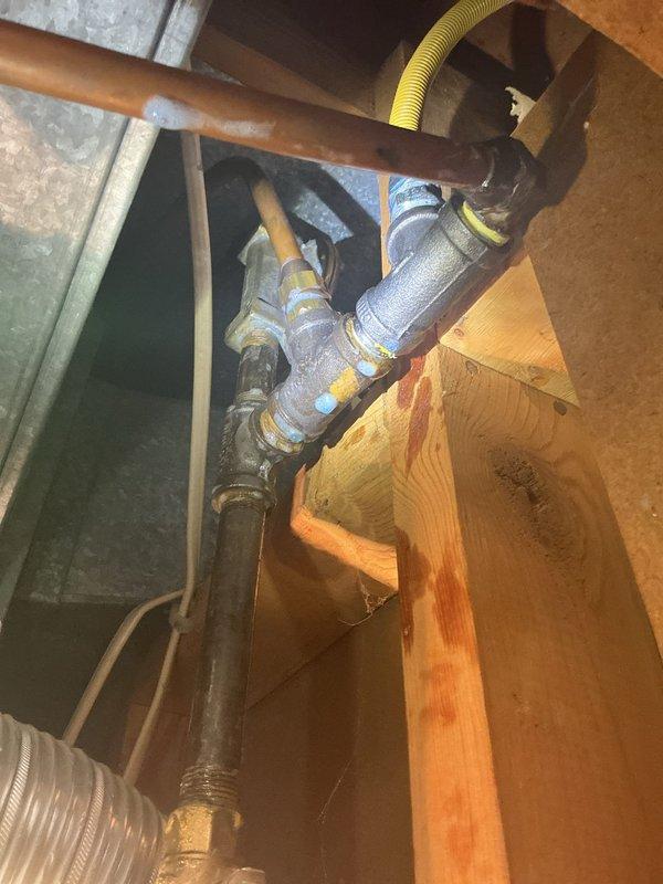 Performed comprehensive inspection of reported gas leak at client's furnace supply line. After thorough assessment using detection equipment, no active gas leaks were identified in the system. Also investigated sewer line for reported root intrusion; visual inspection confirmed no current blockage from tree roots. Documentation photos taken of existing plumbing assembly showing copper supply lines, valves, and connection points in structural space.