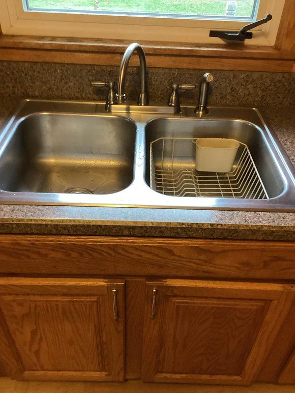 Completed plumbing inspection as part of real estate contingency, documenting conditions of kitchen plumbing fixtures and mechanical room components. Observed functional double-basin stainless steel kitchen sink with gooseneck faucet in good condition, and noted aging brass valve assembly in utility area showing signs of corrosion and mineral buildup that may require future maintenance.