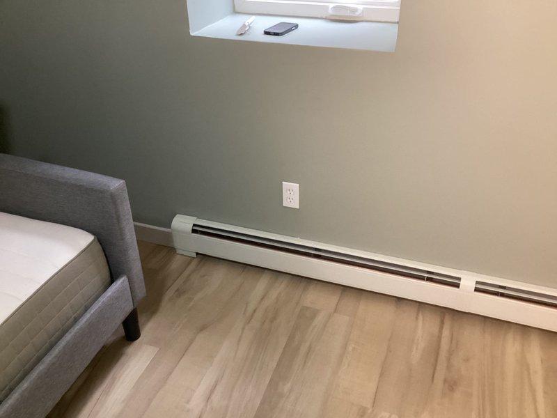 Successfully completed day one of a multi-day hydronic baseboard installation project on the lower level of the home. Began installing various sizes of fin tube baseboard with covers (20', 16', and two 12' sections) in the large room and bedroom. Drained and partially refilled system as part of the ongoing installation process, with work to continue on day two.