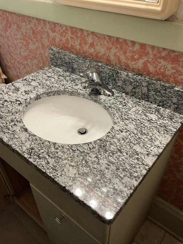 Replaced customer's bathroom sink assembly after previous DIY attempt caused damage. Installed owner-provided granite countertop with undermount ceramic sink, new Moen lavatory faucet, shut-off valves, and supply lines. Corrected issue with spinning shut-off valves that prevented proper water control to the fixture.