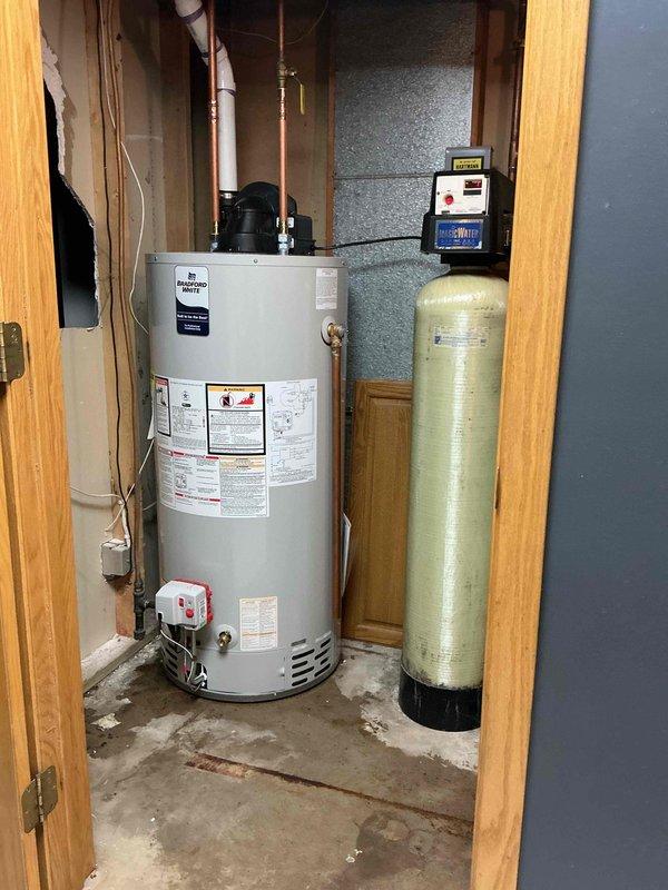 Replaced leaking 50-gallon Bradford White natural gas power vent water heater. Installation included reconnecting copper supply lines and ensuring proper PVC venting. Existing water treatment system was kept intact during the water heater replacement.