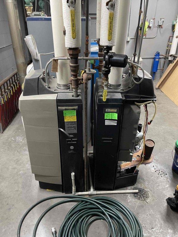 Responded to no-heat call for 13-year-old boiler system with intermittent operation issues. Diagnostic testing revealed gas valve faults on both boilers, which were short cycling and losing flame signal during low modulation. Inspection of the more problematic unit showed severely plugged heat exchanger and damaged burner door gasket. Recommended boiler tune-up and Ultra maintenance with gasket kit. Left problematic boiler disabled due to safety concerns from missing gasket components and potential flue gas leakage. Customer requested email estimates before proceeding with repairs.