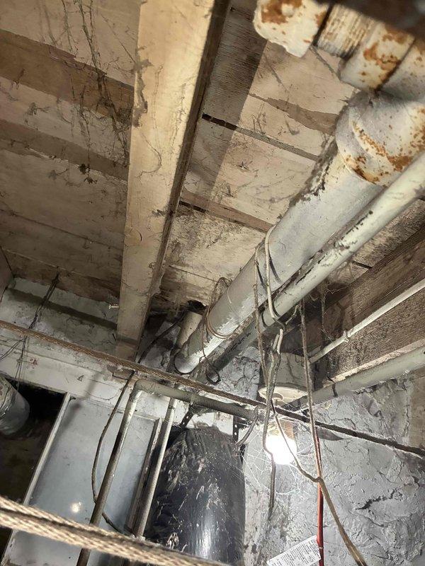 Responded to customer report of toilet leaking from stack originating from upper level. Visual inspection revealed water damage and leaks at cast iron drain pipe and PVC connections in basement area. Successfully pulled and reset toilet to resolve the issue, which was the only toilet in the residence.