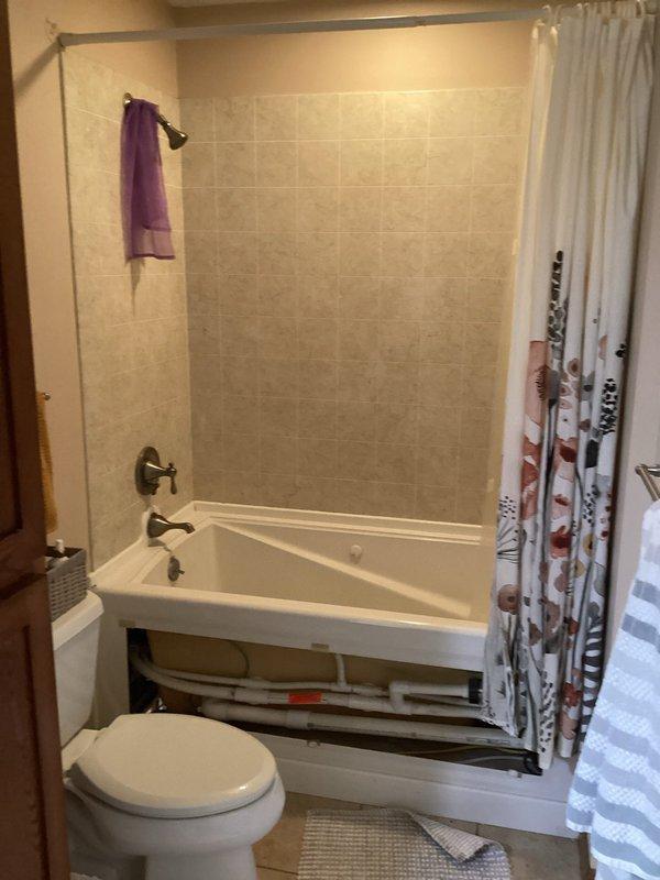 Diagnosed and repaired water leak behind shower that had been penetrating through wall near tub spout. Replaced shower valve to resolve the issue, returning bathroom plumbing to proper working condition.