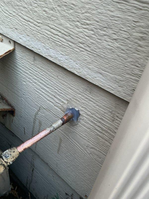 Responded to gas leak emergency where homeowner accidentally severed exterior copper gas line with hedge trimmer. Located damaged section at exterior wall penetration, repaired the copper line by reworking the connection and resealing the wall penetration. Customer must contact gas company to restore service and unlock meter.