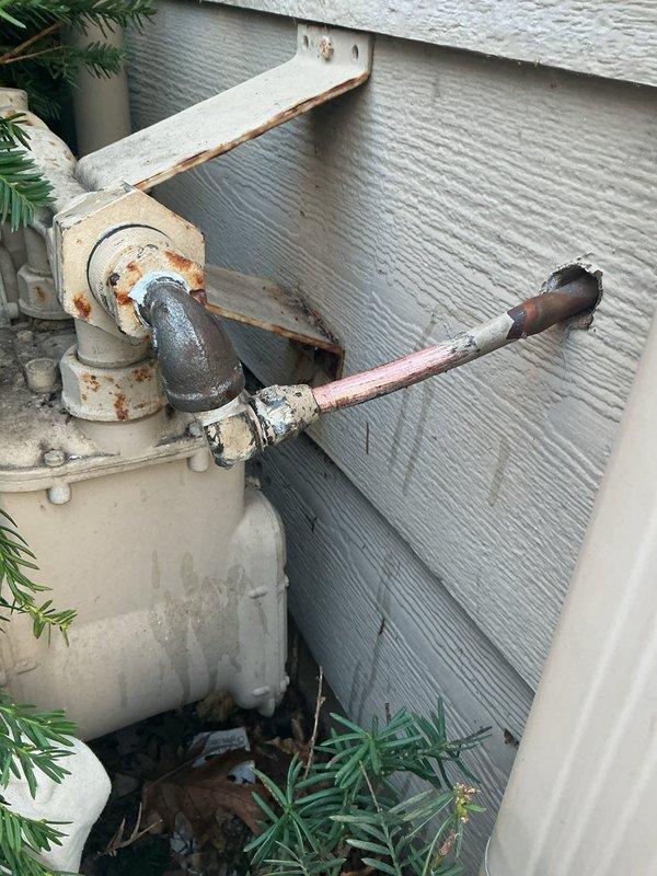 Responded to gas leak emergency where homeowner accidentally severed exterior copper gas line with hedge trimmer. Located damaged section at exterior wall penetration, repaired the copper line by reworking the connection and resealing the wall penetration. Customer must contact gas company to restore service and unlock meter.