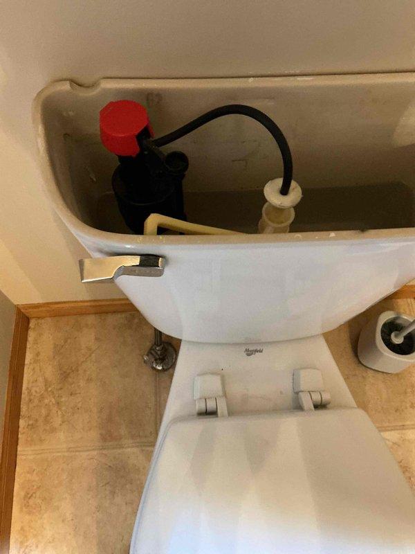 Performed diagnostic assessment on Mansfield standard round toilet experiencing operational issues. Inspected tank components, noting aging flush valve assembly with mineral buildup and wear. Presented customer with repair options including complete rebuild of existing unit or installation of new standard round toilet. Customer advised that repair costs would be approximately half the replacement cost and is considering both options.