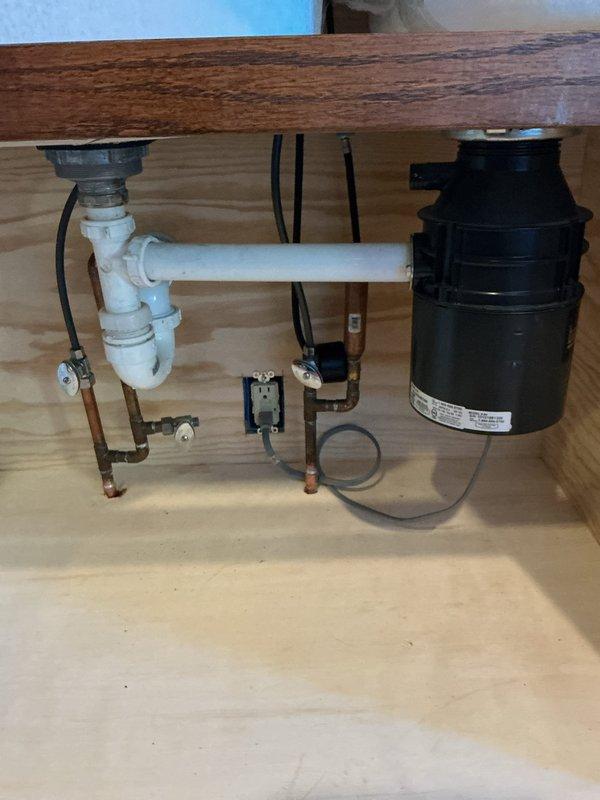 Installed new kitchen faucet and reconnected complete drain assembly including P-trap configuration to double-basin stainless steel sink. Connected copper supply lines to faucet fixture and verified proper drainage system functionality with no leaks present.