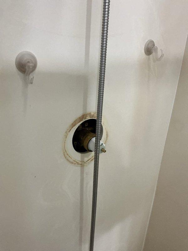 Responded to active water leak in bathroom/bedroom area reported by tenant. Upon inspection, identified a pinhole leak in the brass shower valve causing water to penetrate wall and wet carpet. Cut access to plumbing, removed damaged valve assembly, and replaced shower valve to resolve the issue.
