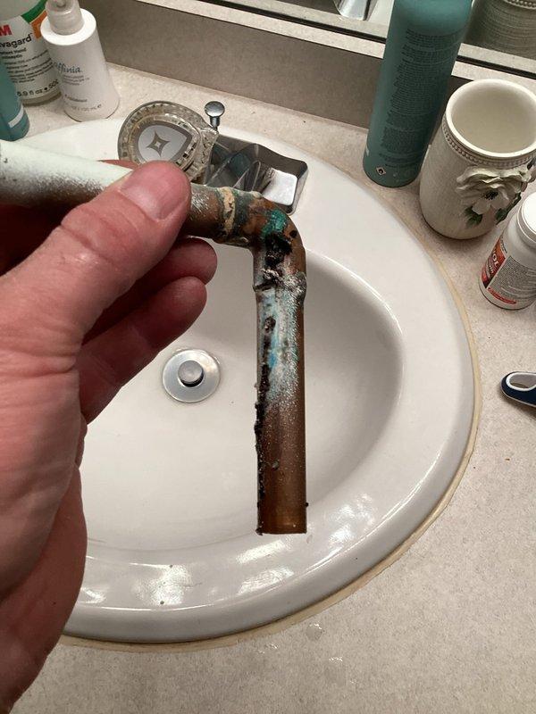 Responded to an emergency leak where water was penetrating from an upstairs bathroom to the lower level. Diagnostic inspection revealed a pin-hole leak in the cold water supply line to the lavatory, with significant copper pipe corrosion evident. Successfully repaired the issue by cutting out the deteriorated section of pipe and installing a replacement connection.