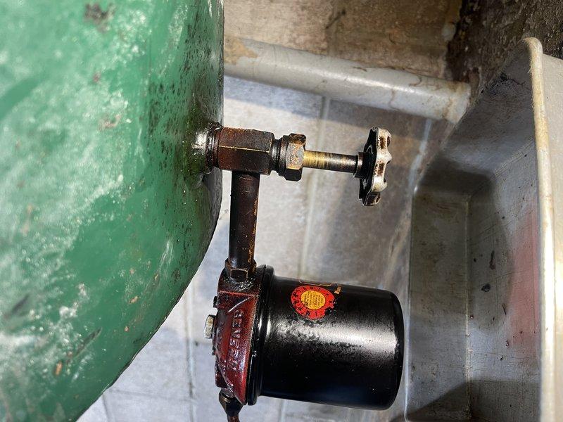 Inspected leaking valve at bottom of customer's fuel oil tank that was previously identified during tune-up service last month. Observed increased dripping since tank was recently filled. Tightened valve nut and cleaned oil residue. Informed customer that complete valve replacement would require emptying the tank first, as the valve is approximately 60 years old.