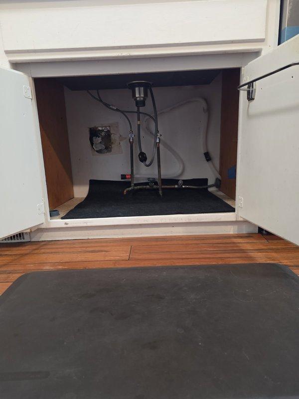 Completed drain rebuild for kitchen sink conversion from dual to single drain configuration. Replaced corroded copper P-trap assembly and installed new connections with proper gaskets. Addressed visible oxidation issues in the plumbing system under the sink cabinet.