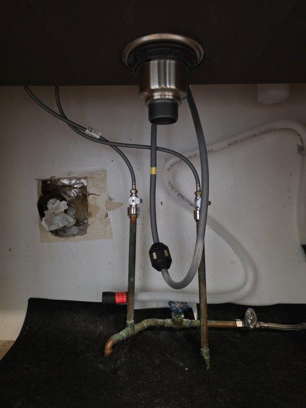 Completed drain rebuild for kitchen sink conversion from dual to single drain configuration. Replaced corroded copper P-trap assembly and installed new connections with proper gaskets. Addressed visible oxidation issues in the plumbing system under the sink cabinet.