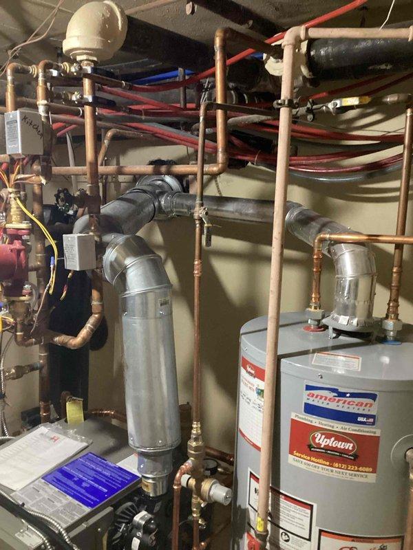 Inspected recently installed boiler following customer complaint of excessive operational noise audible from first floor living space. Observed cast iron boiler with inducer motor emitting vibration. Determined that shared venting configuration with water heater and inadequate support structure is causing noise transmission through the system. Recommended separation of boiler venting from water heater and installation of improved vibration isolation supports to resolve the issue.