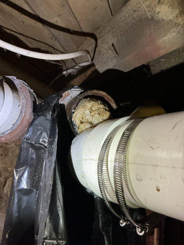 Responded to service call for smart toilet overflowing and leaking from base. Upon inspection, discovered main 4-inch drain line was completely blocked at transition to cast iron pipe. Observed significant deterioration at pipe connection point. Cut open pipe to drain standing water, then made temporary repair to restore functionality. Submitted bid for permanent repair solution due to observed corrosion and deterioration of cast iron waste pipe junction.