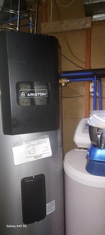 Responded to service call for 1-year-old electric water heater leaking from bottom. Inspection revealed water actively streaming from brass valve connection on supply line with mineral buildup indicating ongoing leak. Determined tank failure requires complete replacement. Informed homeowner of warranty options through original retailer (Home Depot) as unit was not installed by our company.