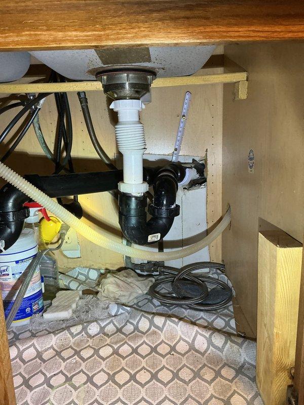 Cleared clogged kitchen sink where water was backing up into disposal side when using the opposite basin. Inspection of under-sink plumbing revealed improper drain line pitch. Raised and adjusted the drain line configuration to improve flow and eliminate backup issues.
