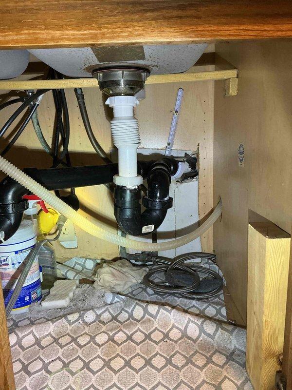 Cleared clogged kitchen sink where water was backing up into disposal side when using the opposite basin. Inspection of under-sink plumbing revealed improper drain line pitch. Raised and adjusted the drain line configuration to improve flow and eliminate backup issues.