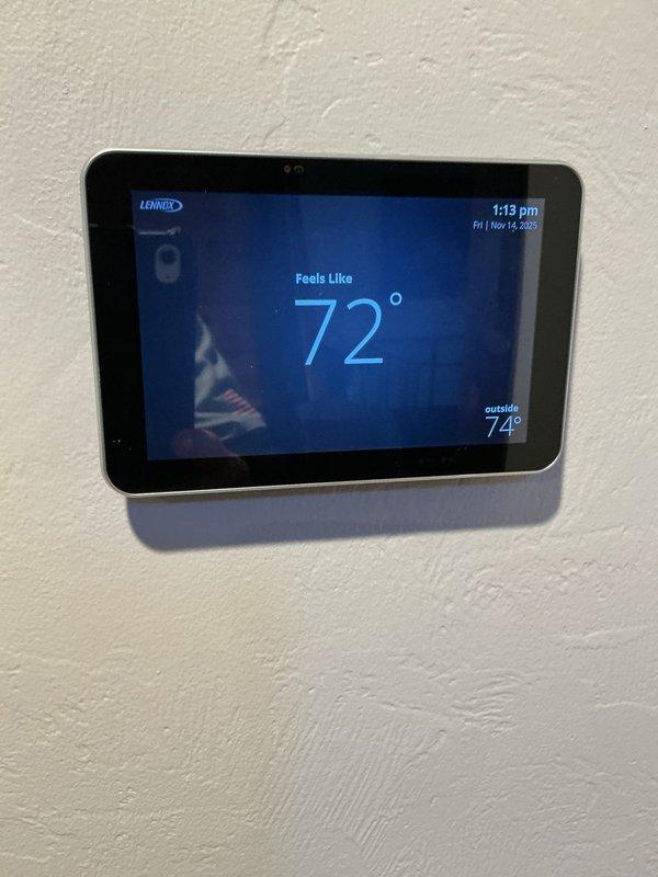 Investigated customer complaint of inaccurate outdoor temperature readings on Lennox thermostat, confirming sensor reads 10-15 degrees higher than actual temperature due to direct sunlight exposure and heat radiation from dark exterior wall. Evaluated thermostat placement concerns related to nearby wood-burning stove causing temperature inconsistencies in distant rooms. Recommended monitoring temperature discrepancies at different times and discussed installation of remote temperature sensors to improve comfort in rooms affected by uneven heating.
