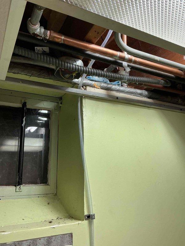 Responded to warranty service call for recurring humidifier leak. Discovered missing drain line causing water damage to adjacent carpet and found condensate pump outlet line severely kinked around ceiling tile. Installed proper humidifier drain line and rerouted condensate pump discharge line to prevent future kinking and leakage issues.