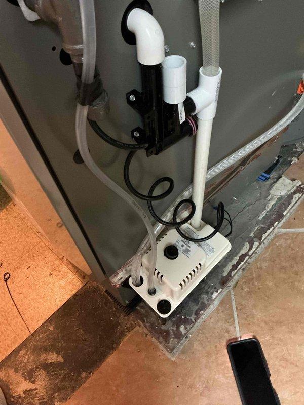 Responded to warranty service call for recurring humidifier leak. Discovered missing drain line causing water damage to adjacent carpet and found condensate pump outlet line severely kinked around ceiling tile. Installed proper humidifier drain line and rerouted condensate pump discharge line to prevent future kinking and leakage issues.