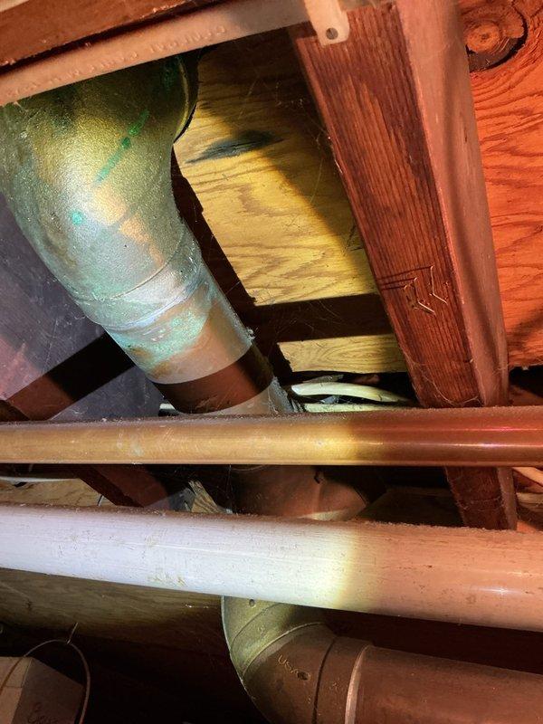 Inspected property for reported water leak and identified a worn-through cast-iron main pipe leading to septic system. Further examination revealed multiple additional leaks in overhead copper piping, with visible oxidation forming green patina on several copper lines. Due to extent of damage throughout the plumbing system, scheduled follow-up for comprehensive assessment and estimate for complete system re-pipe.