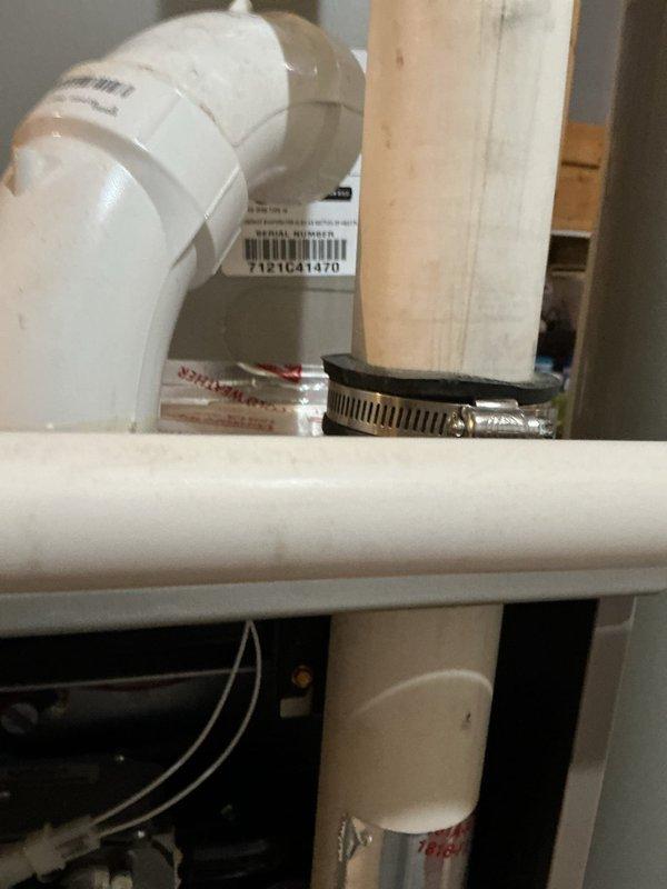 Repaired HVAC system by applying silicone sealant to compromised rubber coupling between inducer motor and vent pipe. Identified significant corrosion at the connection point where black elbow joint meets the white PVC vent pipe. Temporary repair completed; scheduled return visit to replace the deteriorated 90-degree rubber boot assembly.