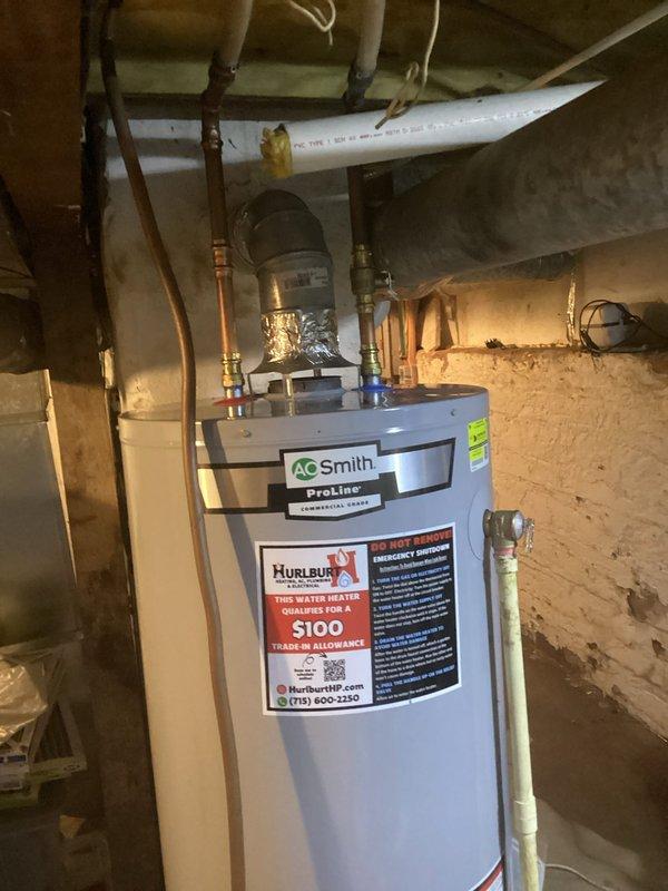 Replaced leaking A.O. Smith ProLine water heater under warranty after diagnosing unit failure. Original 5-year-old unit was leaking from bottom and not producing hot water. Complete installation included reconnecting all necessary copper and PVC piping with appropriate fittings and valves in basement utility area where water treatment system is also located.