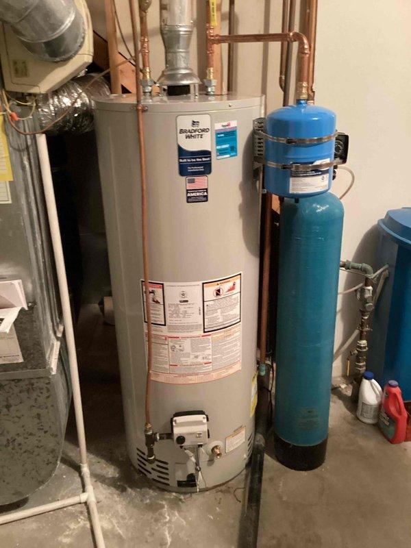 Completed installation of a new toilet as per sold job agreement. While on site, documented the customer's water heating and treatment system, which includes a Bradford White water heater with copper piping connections and a blue water softener/filtration system, both properly installed and functioning in the mechanical room.